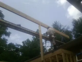 Carpenter setting a ridge beam over a new addition frame — Ice Dam Removal by Roofing Brothers in Tracys Landing