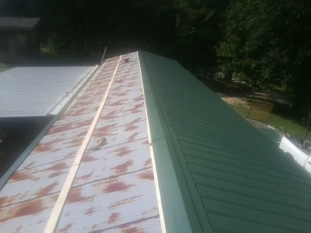Old rusted panels beside newly installed green metal roofing — Wind Damage Roof Repair by Roofing Brothers in Tracys Landing