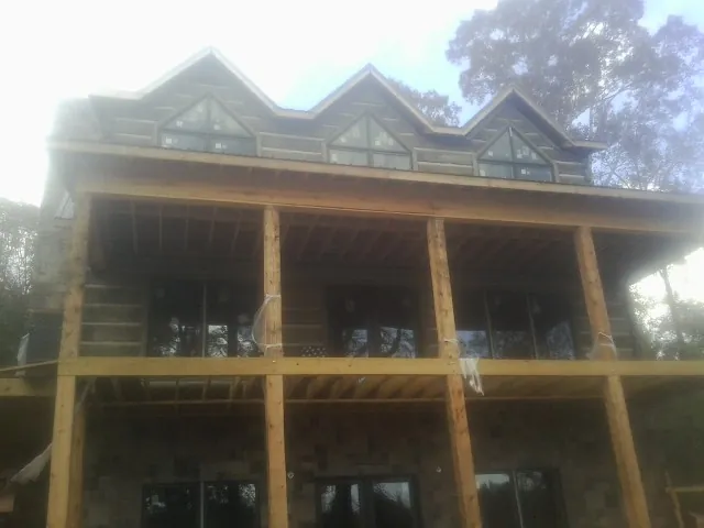 Dormers and porch framing on a large log home under construction — Roof Coating work by our crew in Tracys Landing