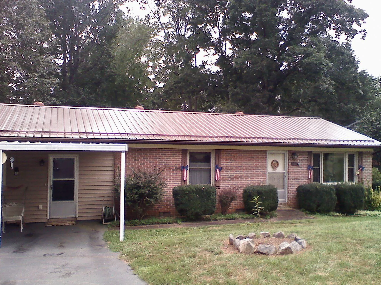 Bronze metal roof and carport on a brick ranch home — Roof Repair work by our crew in Tracys Landing