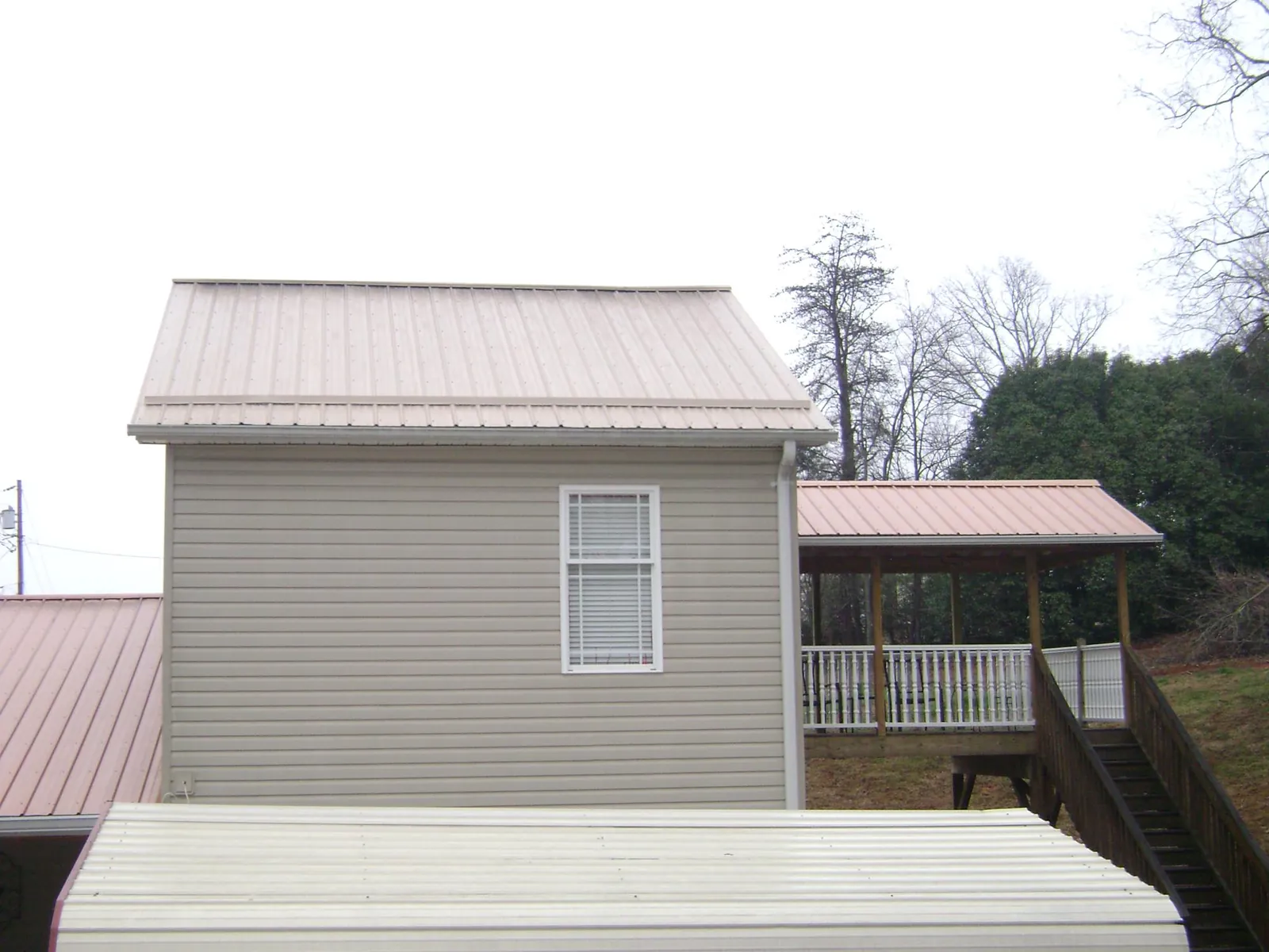 Tan metal roofs on a two story addition and attached porch, from a Roof Replacement job in Tracys Landing