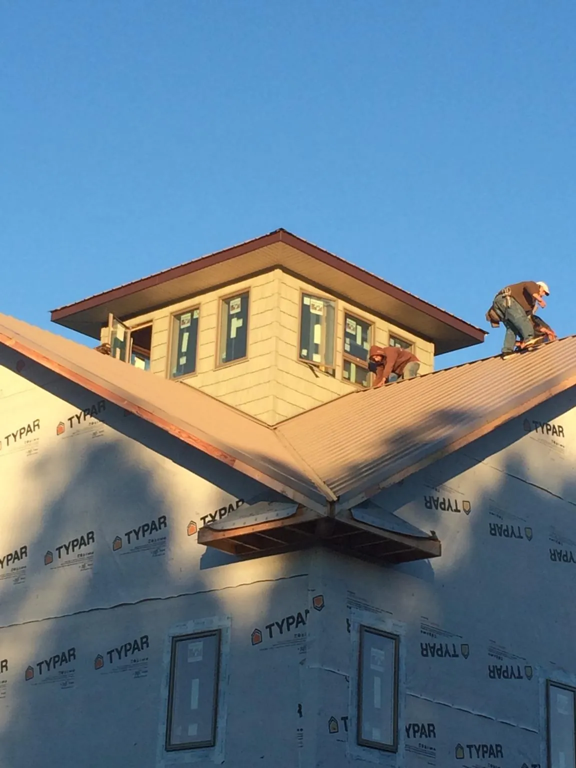 Roofers working around a rooftop cupola on a new metal roof at sunset — Roof Waterproofing in Tracys Landing by Roofing Brothers